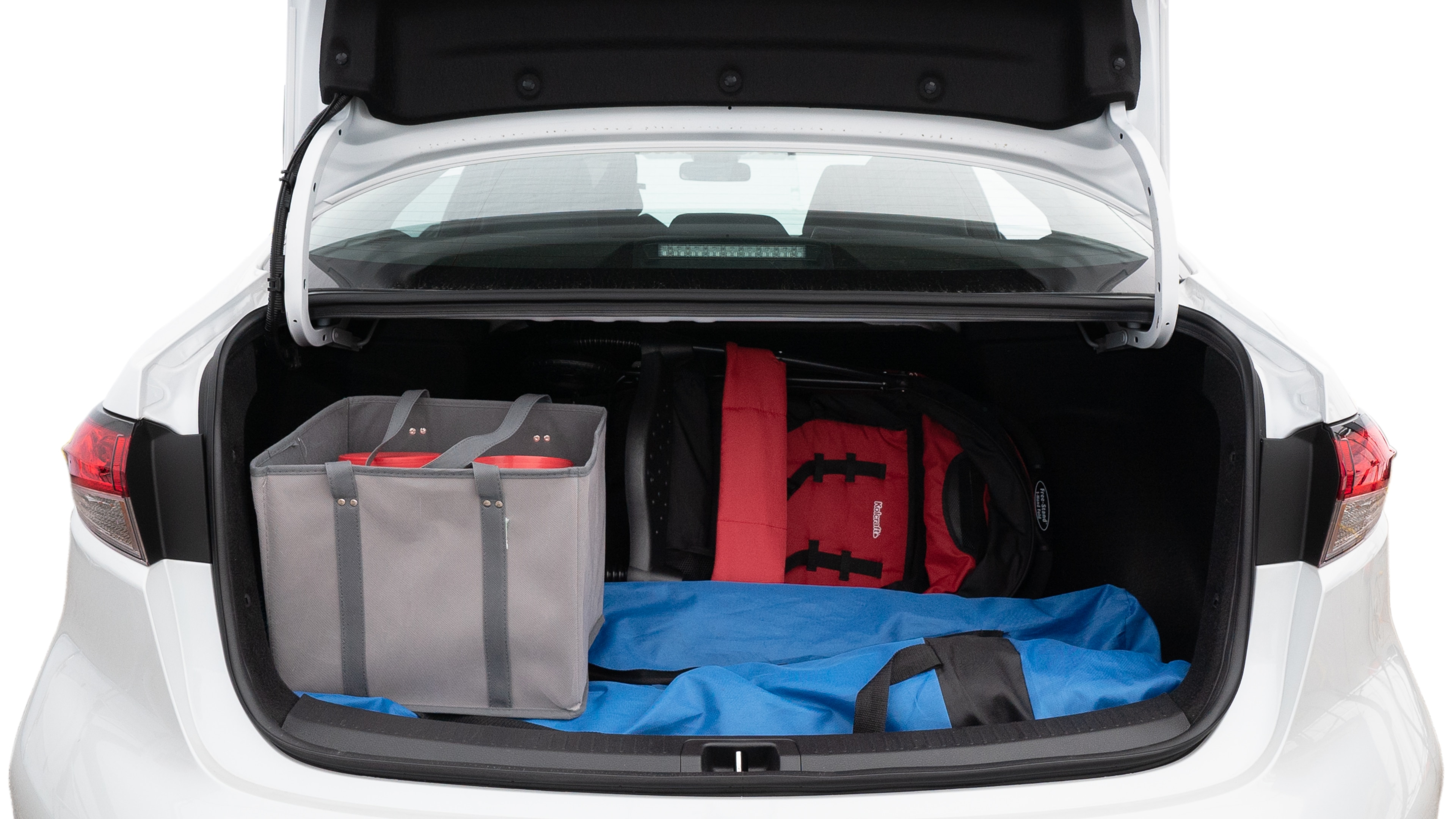 The trunk lid is open showing full view of the trunk. A baby stroller, three grocery carriers, two camping chairs in the carrying bag, and a set of golf clubs are placed inside.
