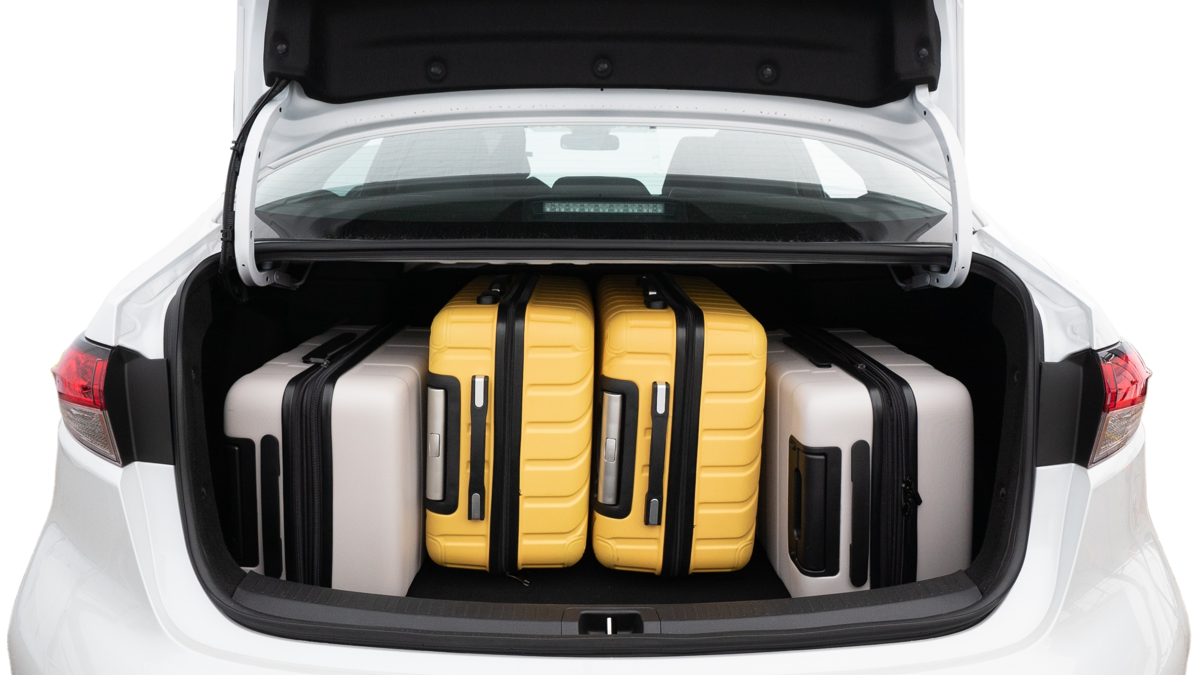 The trunk lid is open, showing full view of the trunk space. Two medium and two small suitcases are placed inside.