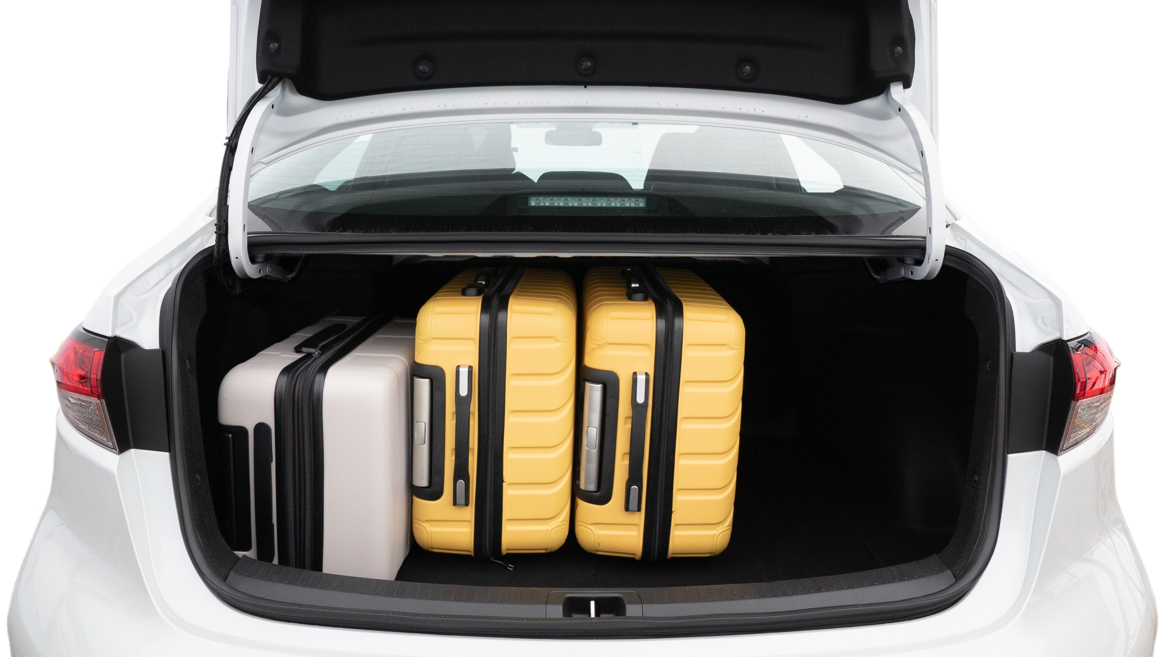 The trunk lid is open, showing full view of the trunk space. Two medium and two small suitcases are placed inside.